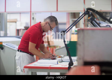 Ingegnere maschio esaminando il circuito stampato nell'industria,Hannover, Bassa Sassonia, Germania Foto Stock