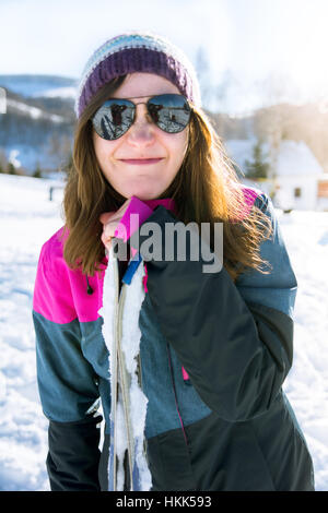 Ragazza facendo una divertente faccia appoggiata su sci outdoor Foto Stock