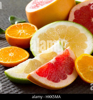Agrumi collezione di fettine di pompelmi e mandarini su una pietra lo sfondo grigio. Frutti di cibo in background. Mangiare sano e la dieta. Foto Stock
