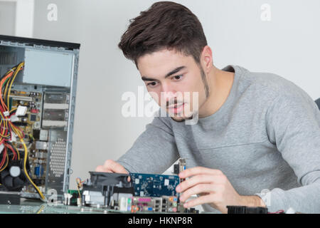 Giovane bello computer riparatore concentrato sul suo lavoro Foto Stock