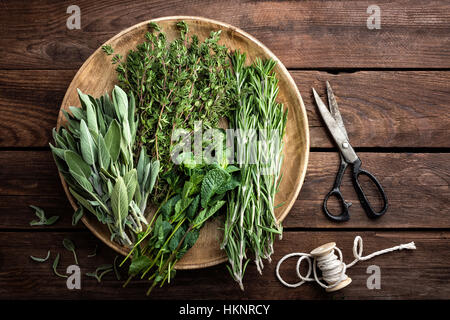 Varie erbe fresche, rosmarino, timo, menta e salvia su sfondo di legno Foto Stock