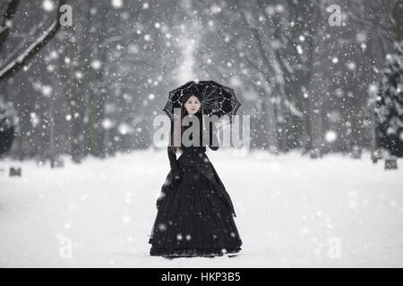 La donna in nero abito vittoriano nel Winter Park Foto Stock