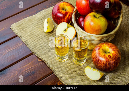 Apple brandy scatti e le mele rosse nel rustico cesto in vimini su sfondo di legno Foto Stock