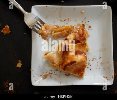 Un individuo aiutando di rustico la torta di mele di essere mangiato con una forcella di argento. Foto Stock