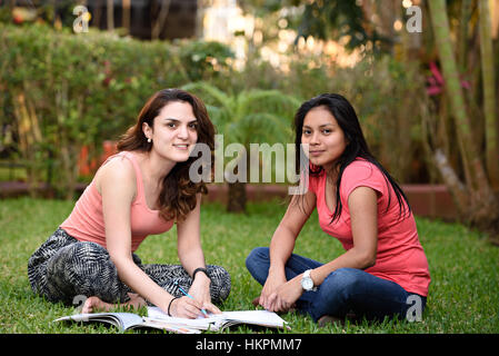 Due ragazze latino studiare la lingua sit erba verde Foto Stock