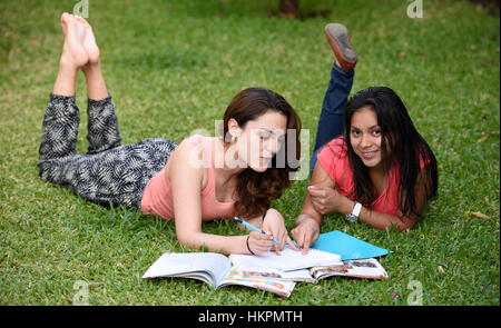 Le ragazze che posa in erba e puntamento in notebook Foto Stock