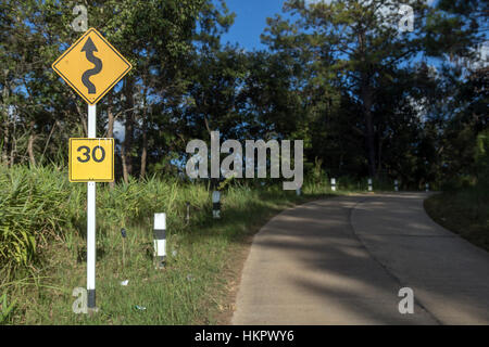 Curva cartello stradale di avvertimento sulla strada di campagna Foto Stock