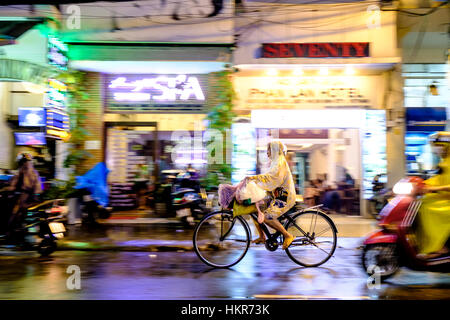 Ciclista in una strada piovosa, ho Chi Minh città (Saigon), Vietnam, Sud-est asiatico Foto Stock