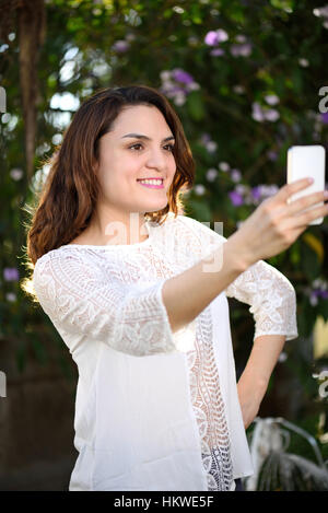 Ragazza ispanica prendere selfie con telefono su green park Foto Stock