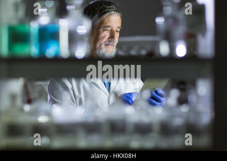 Maschio senior researcher di effettuare attività di ricerca scientifica in un laboratorio (SHALLOW DOF; dai toni di colore immagine) Foto Stock