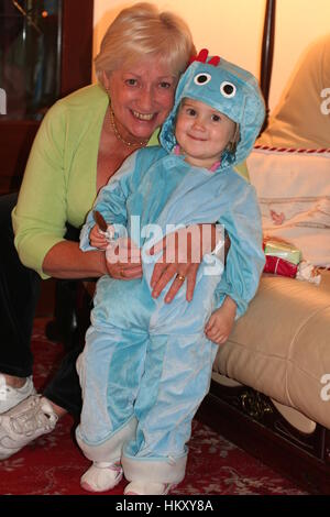 Bambina vestito come Iggle Piggle indossando un cappuccio in velluto blu tuta onesie abbracciando la nonna Foto Stock