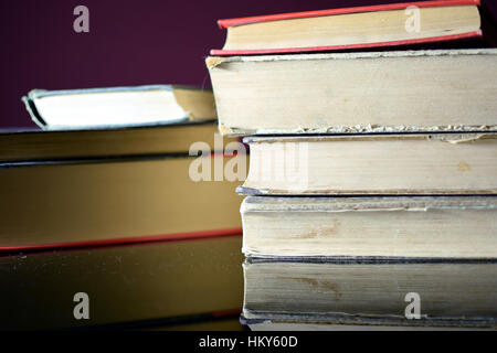 Due pile di libri vecchi su nero tavolo specchiante. Foto Stock