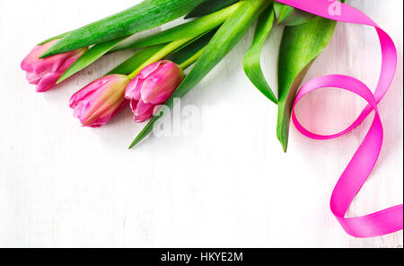 Tulipani a molla sul bianco sullo sfondo di legno, vista dall'alto Foto Stock