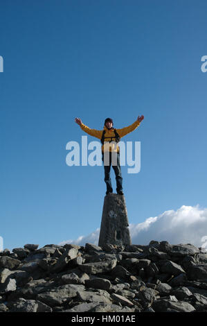 Hill walker in piedi sul punto di innesco che ondeggia con entrambe le braccia sulla luminosa giornata di sole Foto Stock