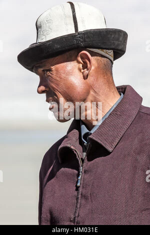 Uomo del Kirghizistan nei tradizionali hat pone in campagna montuosa dell altopiano del Pamir dalla Karakoram Highway, Xijiang, Cina. Foto Stock