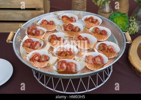 Salsicce di BBQ avvolto in pancetta sulla bella decorazione tavola, close up Foto Stock