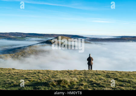 Una femmina di un escursionista si ammira la vista dopo l'alba in un freddo inverno mattina nella speranza Valley. Mam Tor, Peak District Foto Stock