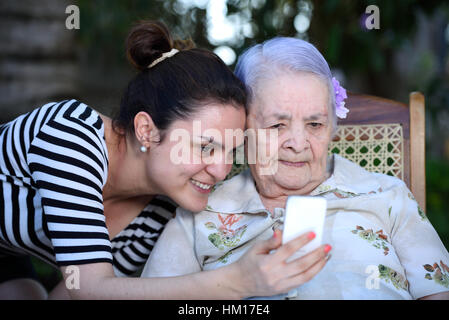 La nonna di prendere foto con i nipoti sul telefono bianco Foto Stock