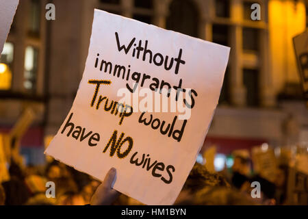 Un manifestante detiene un cartellone di criticare il Presidente Trump's divieto di persone provenienti da alcuni paesi musulmani in viaggio per gli Stati Uniti in un rally di oltre mille persone si sono stretti a Cardiff. La gente ha intonato il sostegno ai rifugiati e contro il fascismo. Foto Stock