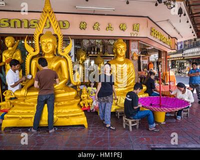 Bangkok, Tailandia. Il 1° febbraio 2017. Gli uomini lavorano su una grande statua del Buddha mentre le donne fanno grandi ombrelloni tradizionali in un negozio che vende e fornisce paraphernalia buddista di Bangkok. Gli ombrelli sono utilizzati come ombrelloni per mantenere il sole spento importanti statue di Buddha e a eventi formali. Nella cultura tailandese, gli ombrelloni sono stati usati per fornire ombra per i membri della famiglia reale o i rappresentanti della famiglia reale. Credit: Jack Kurtz/ZUMA filo/Alamy Live News Foto Stock