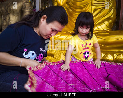 Bangkok, Tailandia. Il 1° febbraio 2017. Una ragazza e sua madre per lavorare su un grande ombrellone tradizionale in un negozio che vende e fornisce paraphernalia buddista di Bangkok. Gli ombrelli sono utilizzati come ombrelloni per mantenere il sole spento importanti statue di Buddha e a eventi formali. Nella cultura tailandese, gli ombrelloni sono stati usati per fornire ombra per i membri della famiglia reale o i rappresentanti della famiglia reale. Credit: Jack Kurtz/ZUMA filo/Alamy Live News Foto Stock