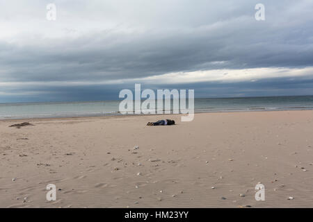 Giovane sdraiato sulla spiaggia abbracciare in Whitepark Bay, Foto Stock