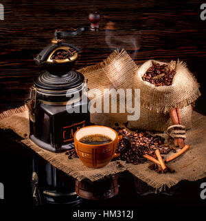 Tazza di caffè, fagioli, mulino manuale sul saccheggio tavolo lucido Foto Stock