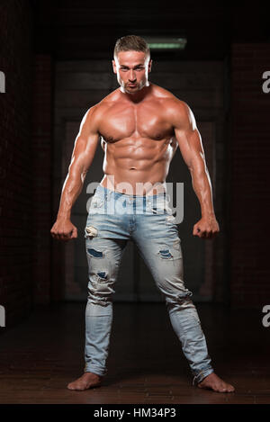 Ritratto di un giovane fisicamente uomo In Jeans che mostra il suo ben addestrato corpo - Atletico muscolare Bodybuilder Modello di Fitness in posa dopo esercizi Foto Stock