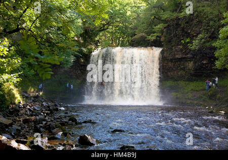 I visitatori cammineranno dietro la cascata Sgwd-yr-Eira vicino Penderyn nel Brecons del Galles del Sud Foto Stock