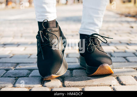 Le donne in piedi in scarpe nere sul marciapiede in una giornata di sole Foto Stock