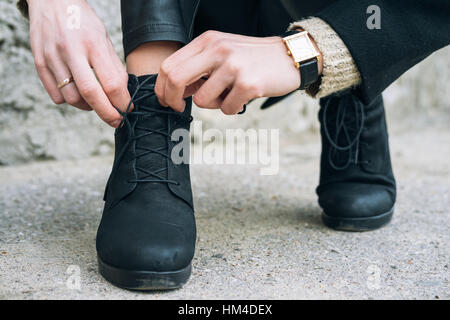 Donna in abiti eleganti lacci delle scarpe di legatura sulle scarpe vicino. Lacci delle scarpe slegato durante una passeggiata in città Foto Stock