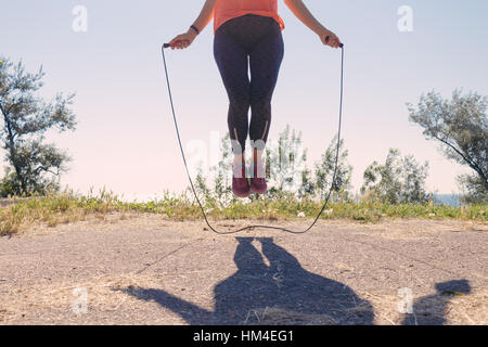 I piedi femminili in sneakers saltando su una corda da salto in estate Foto Stock