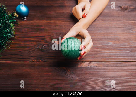Green palla di Natale in una mano femminile con il rosso smalto per unghie Foto Stock