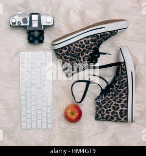 Stile di vita laicale piatta con leopard stivali stampa vecchia fotocamera e tastiera Apple su un tappeto di pelliccia Foto Stock