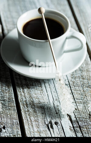 Lo zucchero cristallizzato sul bastone di legno e la tazza di caffè sul vecchio tavolo in legno. Foto Stock