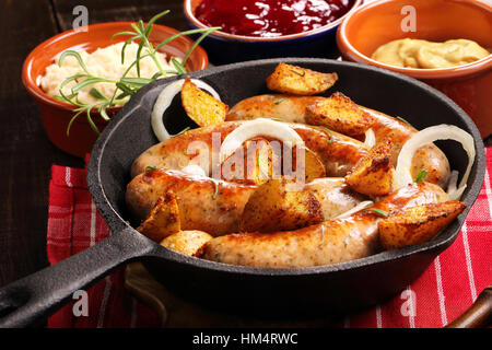 Salsicce bianche con patate al forno in padella Foto Stock