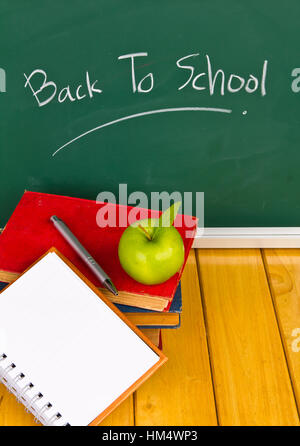 Si torna a scuola scritta sulla lavagna con mela verde e libri Foto Stock