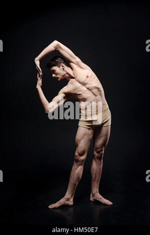 Graziosa ballerina stretching in studio Foto Stock