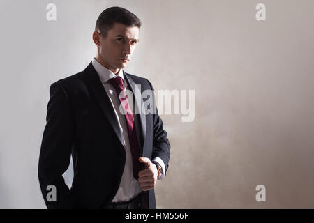 Giovane uomo in uno smoking con cravatta. Si adegua la sua giacca Foto Stock