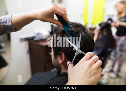 Irriconoscibile parrucchiere il taglio di capelli della sua giovane client. Foto Stock