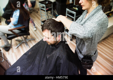 Irriconoscibile parrucchiere il taglio di capelli della sua giovane client. Foto Stock