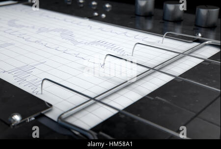 Un 3D rendering di un poligrafo lie detector disegno macchina linee rosse su un foglio di carta millimetrata Foto Stock