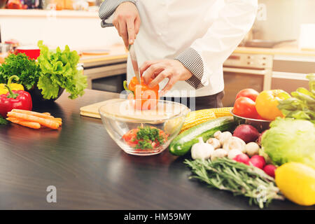 Chef paprika di taglio per insalata di verdure in cucina Foto Stock