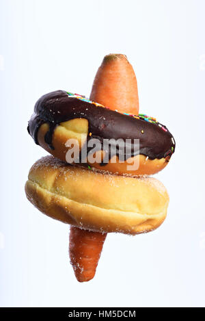 Due ciambelle appendere su carota isolato su bianco Foto Stock