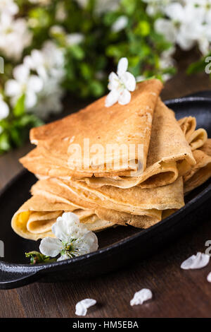 Crepes fatte in casa piegato in triangoli in padella sulla molla sfondo blossom Foto Stock