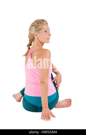 Corpo laterale vista di profilo di una donna bionda di mezza età nella posizione di Yoga seduta flessione in avanti (Paschimothanasana) contro w Foto Stock