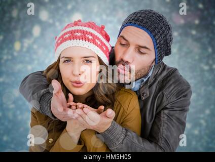 Giovane soffiando baci contro blu sfondo bokeh di fondo Foto Stock