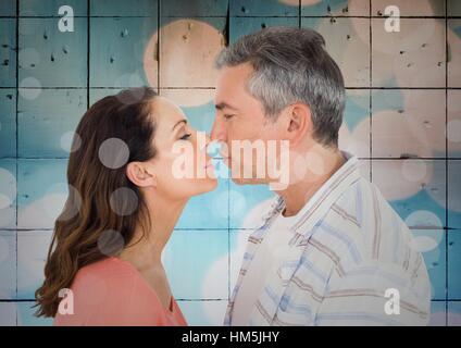 Immagine composita della giovane kissing contro le tessere blu con bokeh di fondo Foto Stock