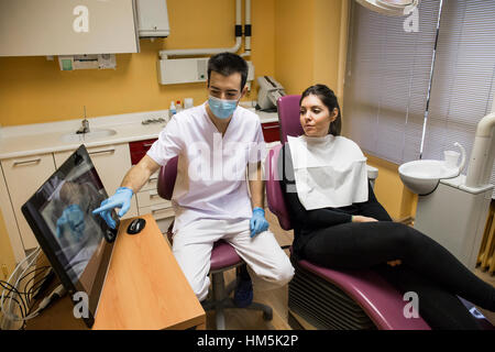 Dentista spiegando x-ray relazione sul computer desktop al paziente durante la seduta in clinica Foto Stock