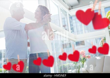 Immagine composita di appesi cuori rossi e coppia matura dancing Foto Stock